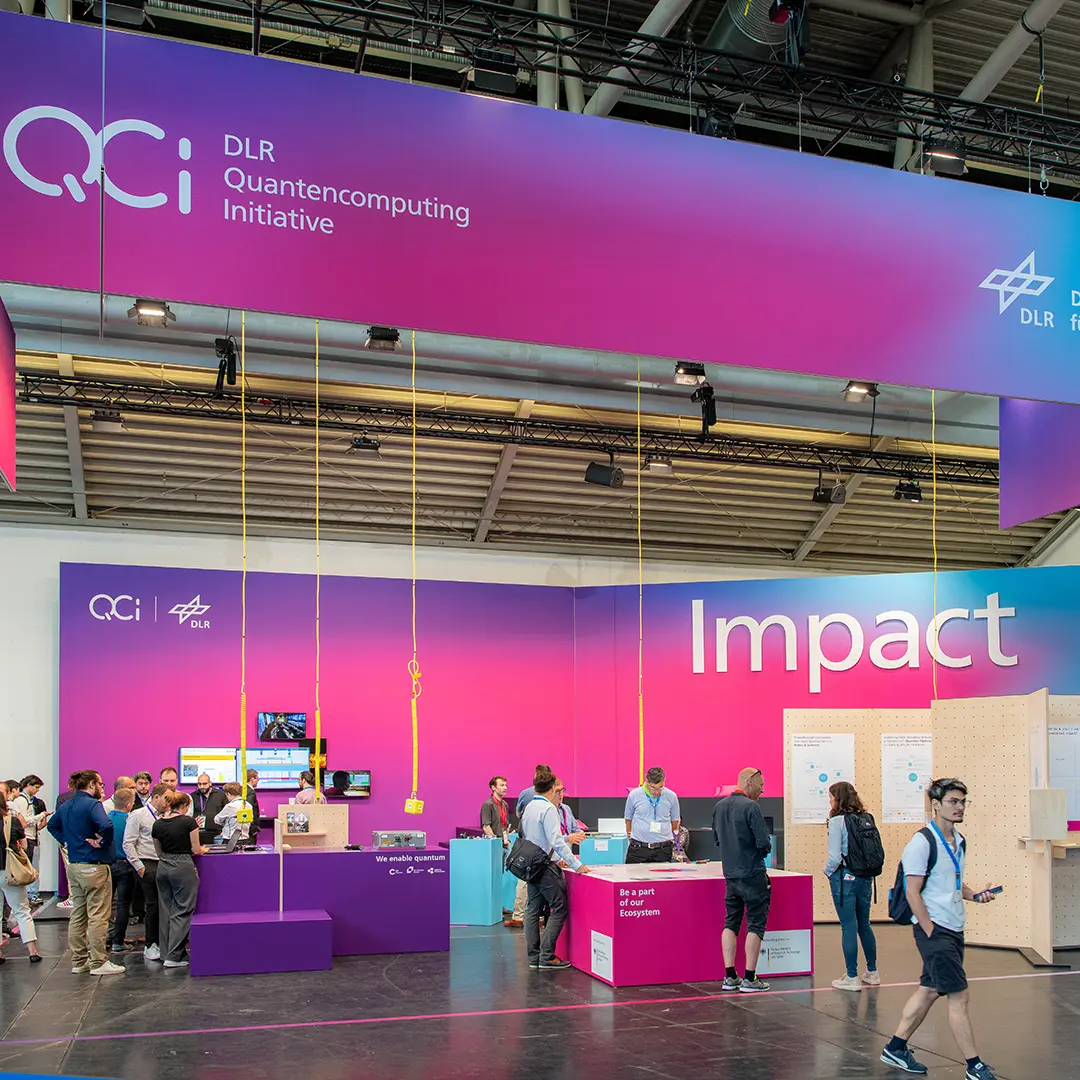 World of Quantum und AFQC 2025 - Interessierte Besucher stehen am Messestand